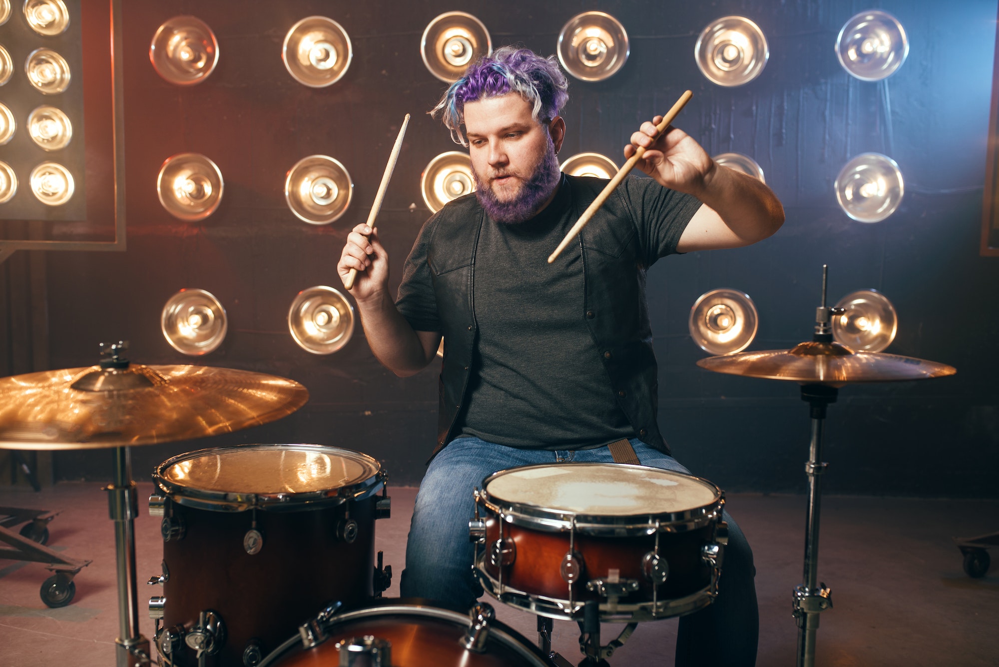 Bearded drummer with colorful hair on the stage