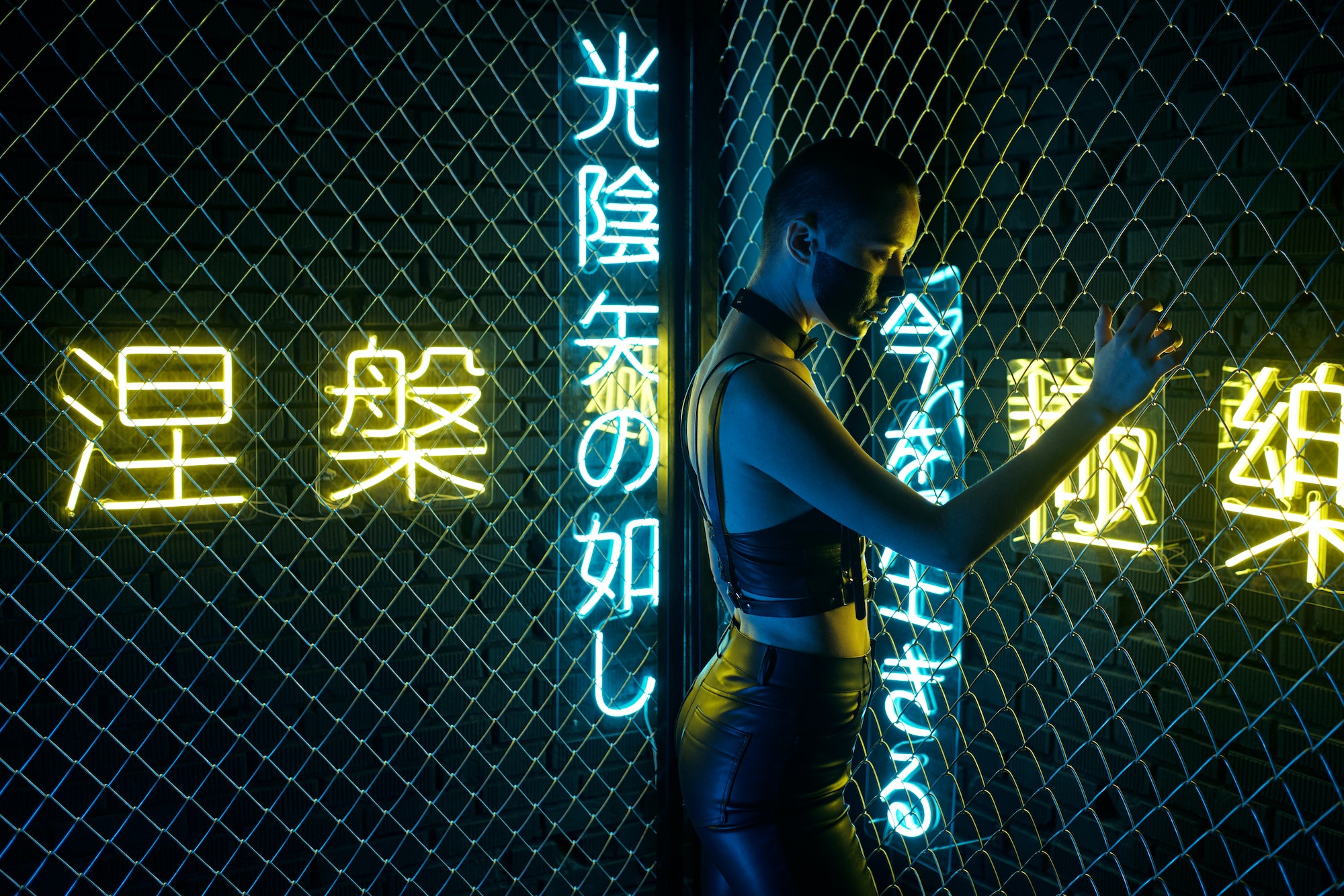 Cyborg girl in black leather clothes standing behind bars
