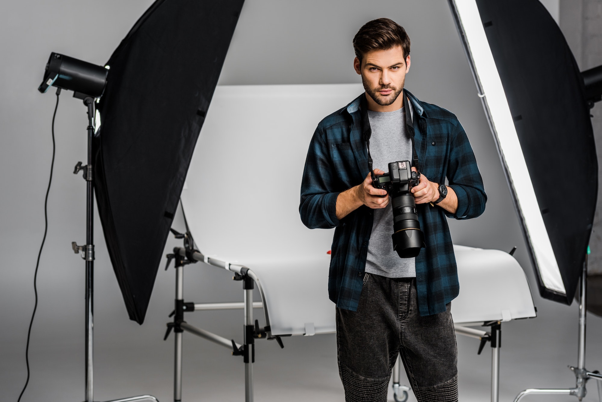 handsome professional young photographer using camera in photo studio