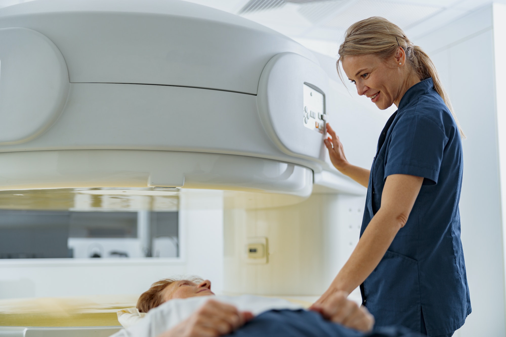 Radiologist controls MRI or CT or PET Scan with female patient undergoing procedure