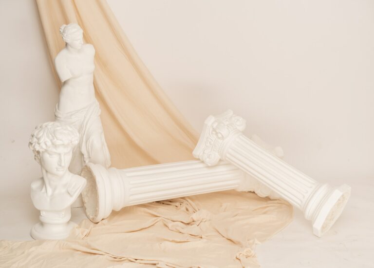 Renaissance epoch gypsum statues arranged with fabric on white background