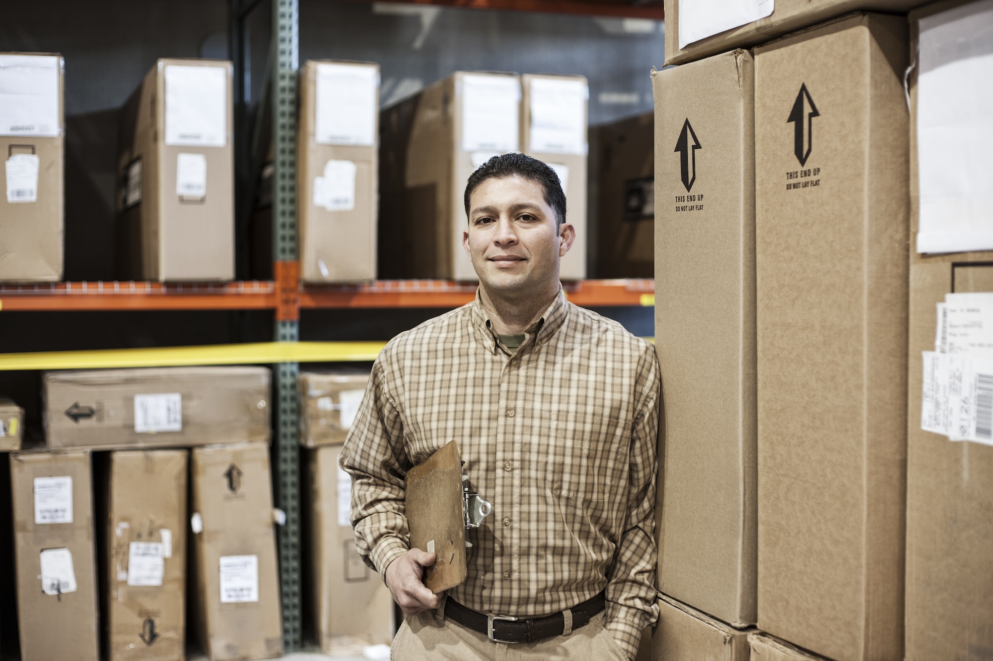 Warehouse worker among racks of boxed products in a distribution warehouse.