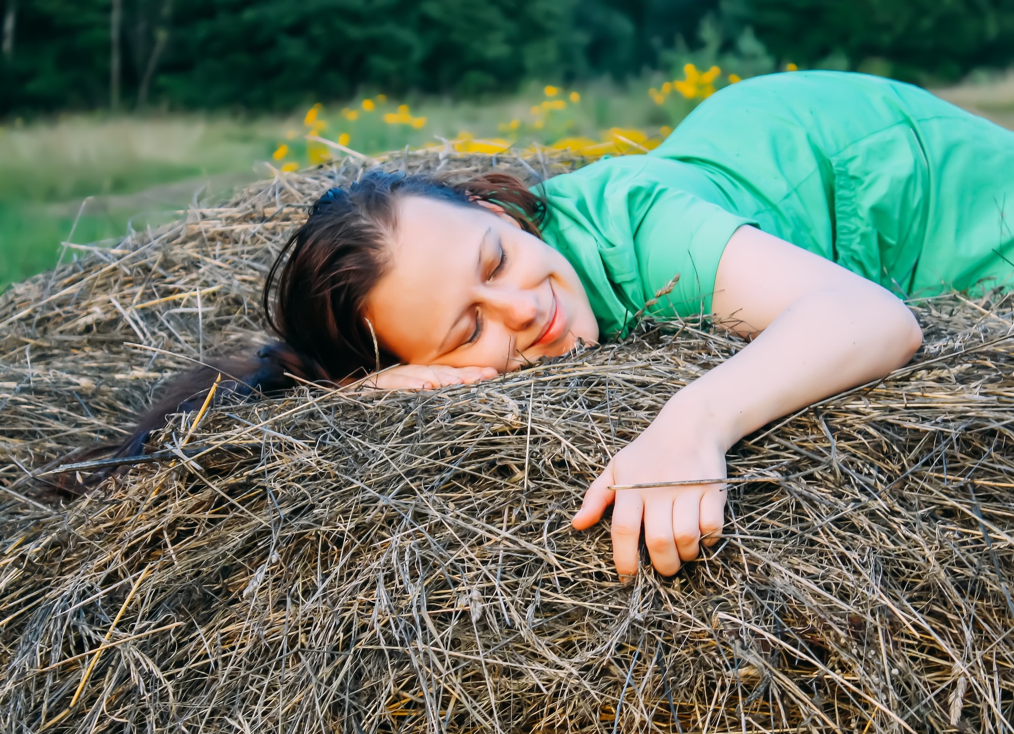 Young attractive woman relaxing on the haystack in the countryside.